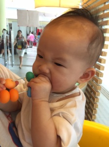 Cutie trying to test if Mummy's teething necklace is made of Gold